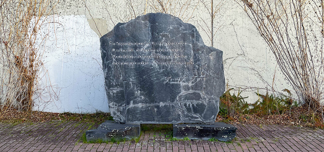 Der graue Heine-Stein steht vor der Außenwand des Hörsaal 3A.