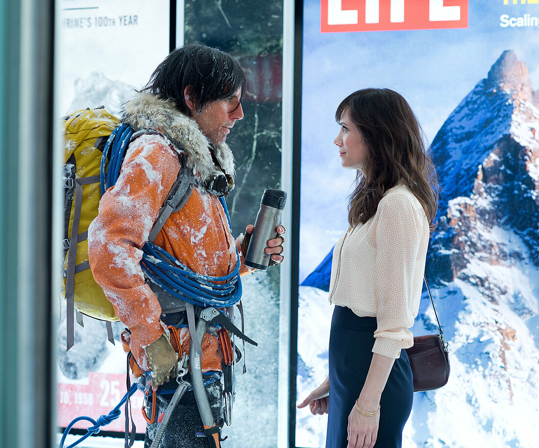 Auf dem Bild sieht man Walter Mitty als Bergsteiger in voller Ausrüstung und Cheryl Melhoff. Die beiden stehen sich in einer verschneiten Umgebung gegenüber.