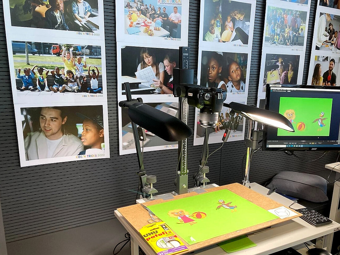 Am Stand von KIDS 'N TRICKS wird gezeigt, wie die Stop-Motion-Bilder der Kinder auf einem grünen Hintergrund abfotografiert und digitalisiert werden. Im Hintergrund Impressionen aus den vergangenen Projekten zu sehen.