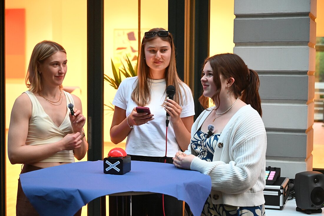 Auf dem Foto sieht man Theresa und Marie, die an einem Tisch gegenüber stehen und bei einem cm3-Quiz für Social Media antreten