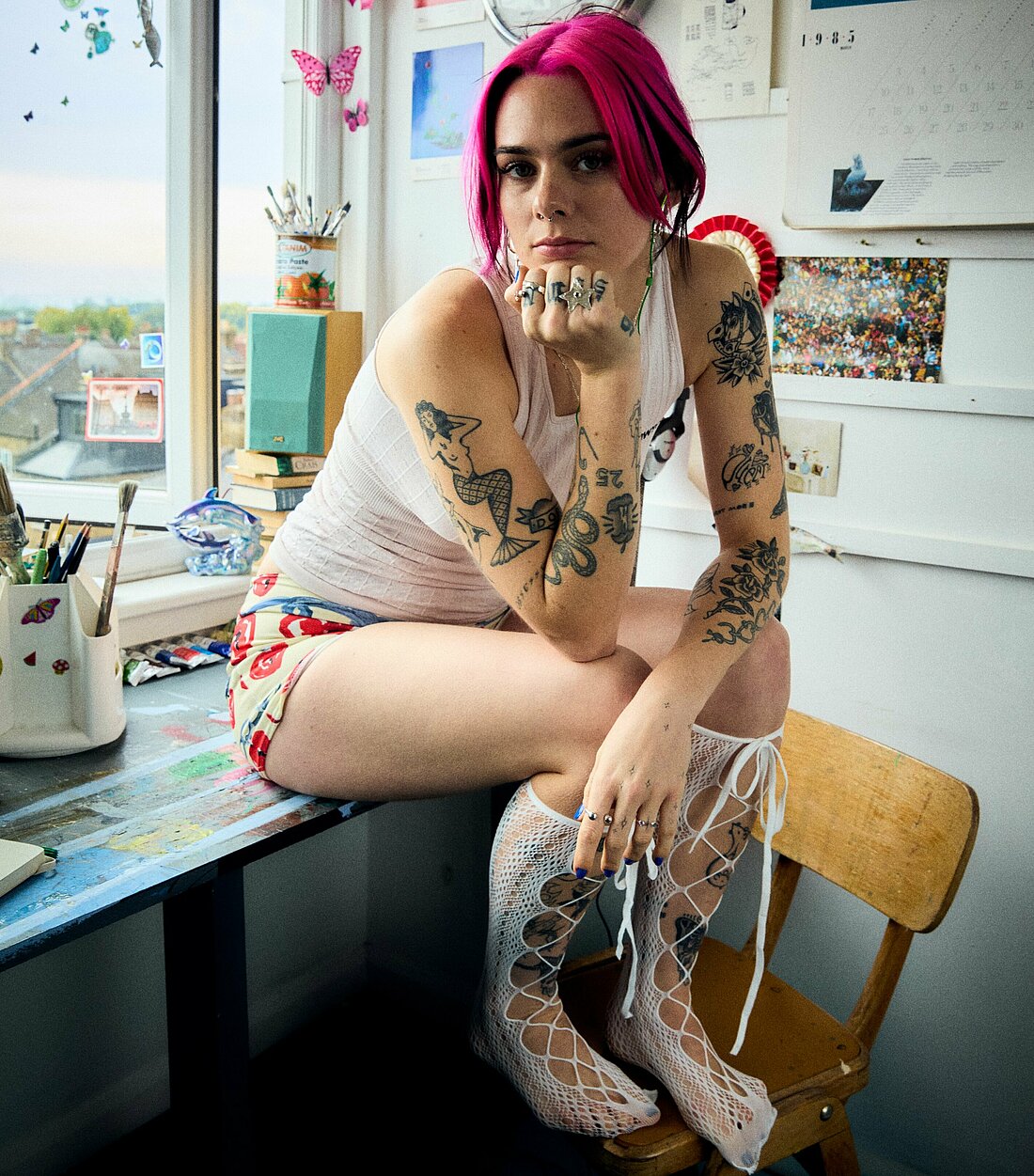 Auf dem Foto sieht man die Pop-Sängerin girli auf einem Tisch sitzen. Sie schaut direkt in die Kamera.