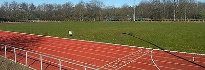 Auf dem Bild sieht man die Laufbahn der Heinrich-Heine Universität in Düsseldorf. Im Hintergrund ist der Rasenplatz mit Fußballtoren auf beiden Seiten sichtbar.