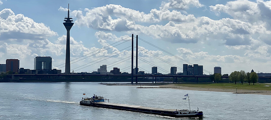Auf dem Foto sieht man die Skyline von Düsseldorf mit dem Rhein im Vordergrund. Hinten sieht man den Rheinturm und den Medienhafen