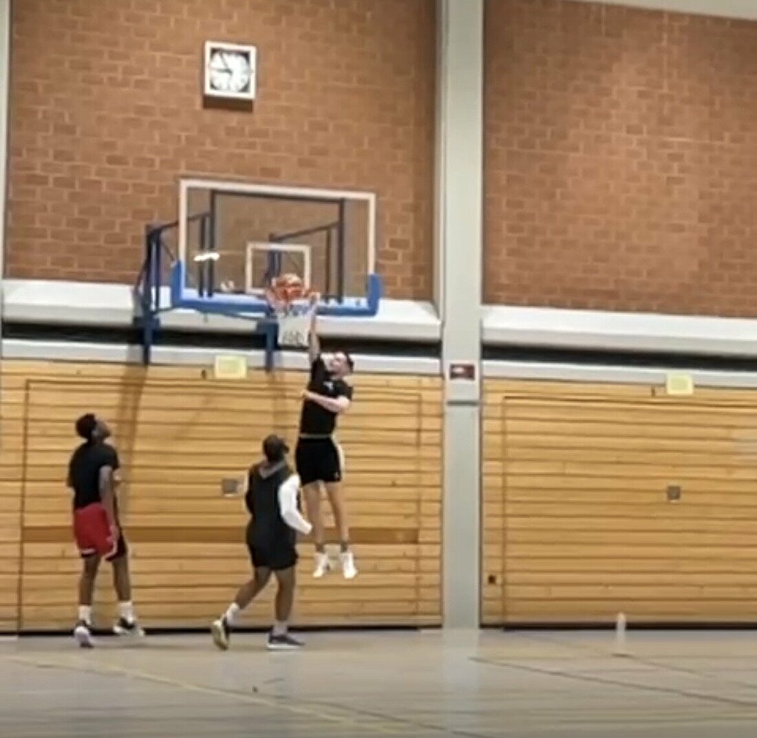 Auf dem Bild sind zwei Basketballspieler zu sehen, die beim Hochschulsport gegeneinander auf einen Korb spielen.