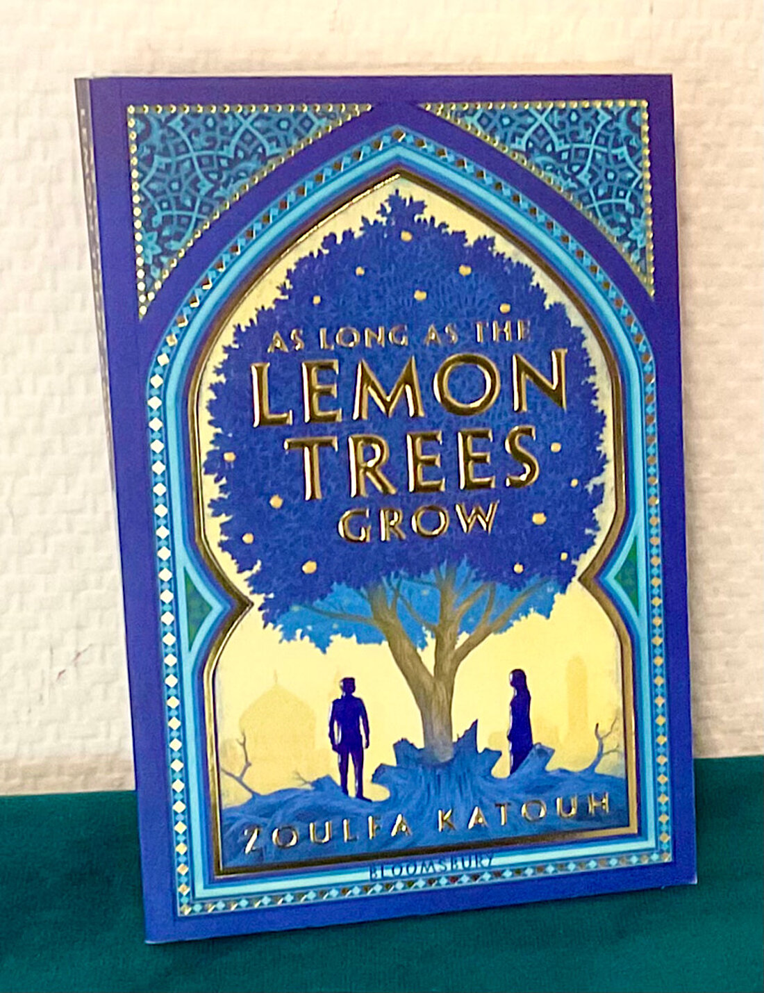 Man sieht das Buchcover des Romans “As Long as the Lemon Trees Grow”