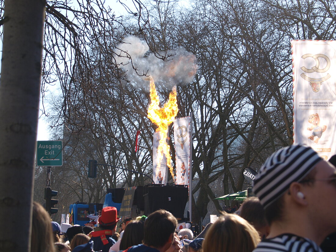 Ein Festwagen aus welchem Rauch und Feuer kommen und zwei Feuer Schweife an ein X bilden.
