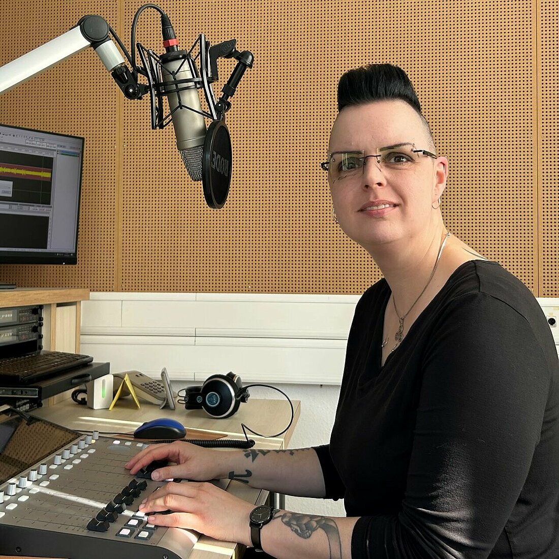 Auf dem Foto ist Yasemin Kizilirmak zu sehen. Sie sitzt im Studio von hochschulradio düsseldorf vor einem Mischpult und schaut in die Kamera.
