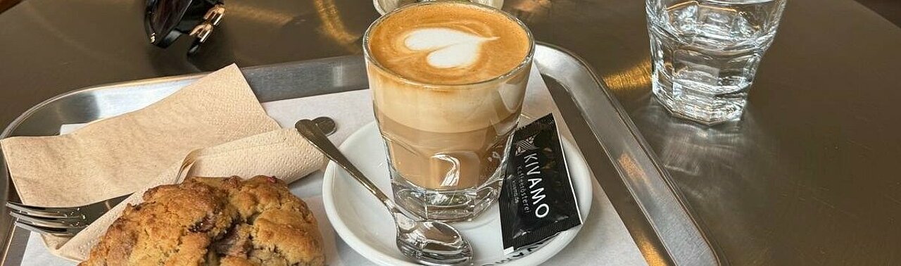 Auf dem Bild sieht man eine Kaffee Spezialität und einen Cookie