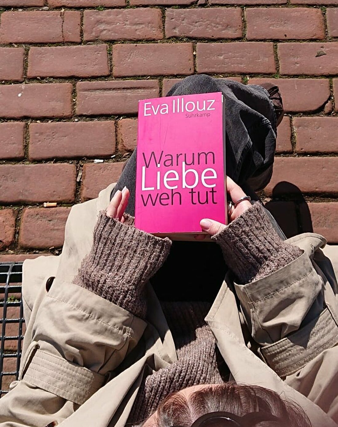 Das Bild zeigt von oben das Buch "Warum Liebe weh tut" von Eva Illouz. Es wird von einer Studentin in den Händen gehalten.