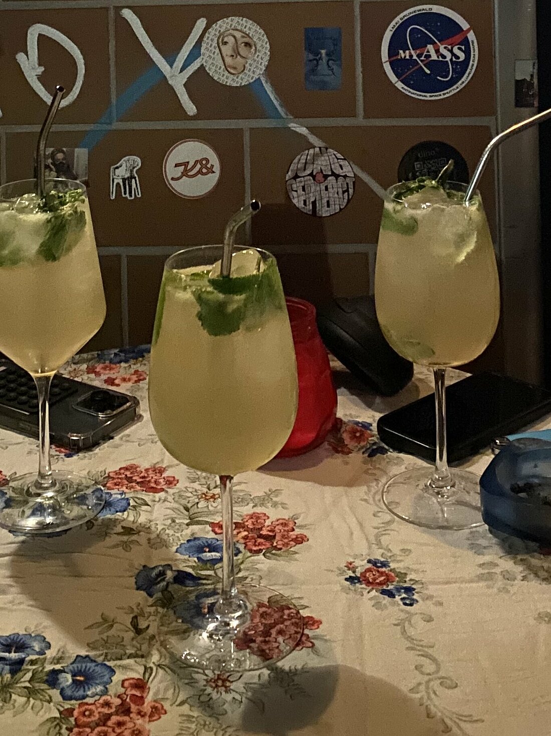 Auf dem Foto sieht man drei Weingläser mit einem Strohhalm. Es sind alkoholfreie Getränke in einer Bar.