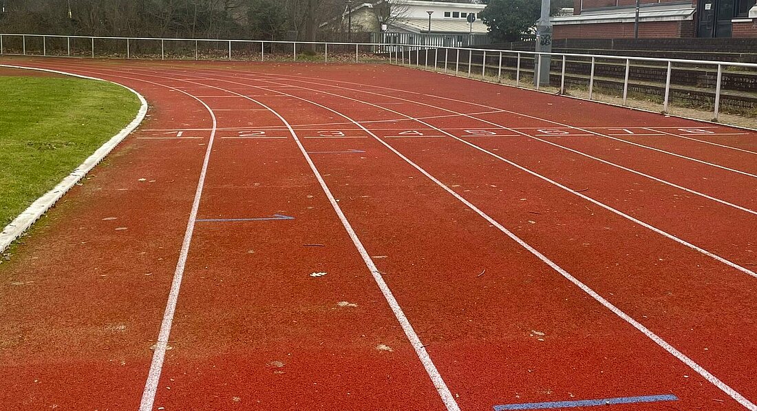 Auf dem Bild sieht man eine Laufbahn. Auf dem Boden sind die Zahlen eins bis neun eingetragen für die Läufer.