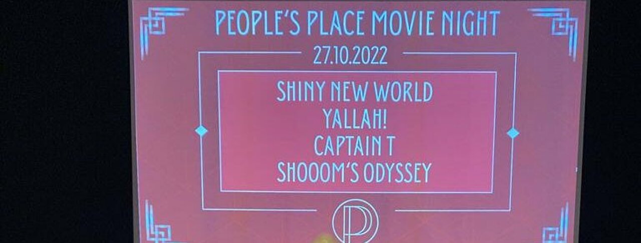 Zusehen ist eine Leinwand mit der Projektion: "Plakat der Peoples Place Movie Night" und den Namen der vier FIlme: Shiny New World, Yallah, Captain T, Shrooms Odyssey