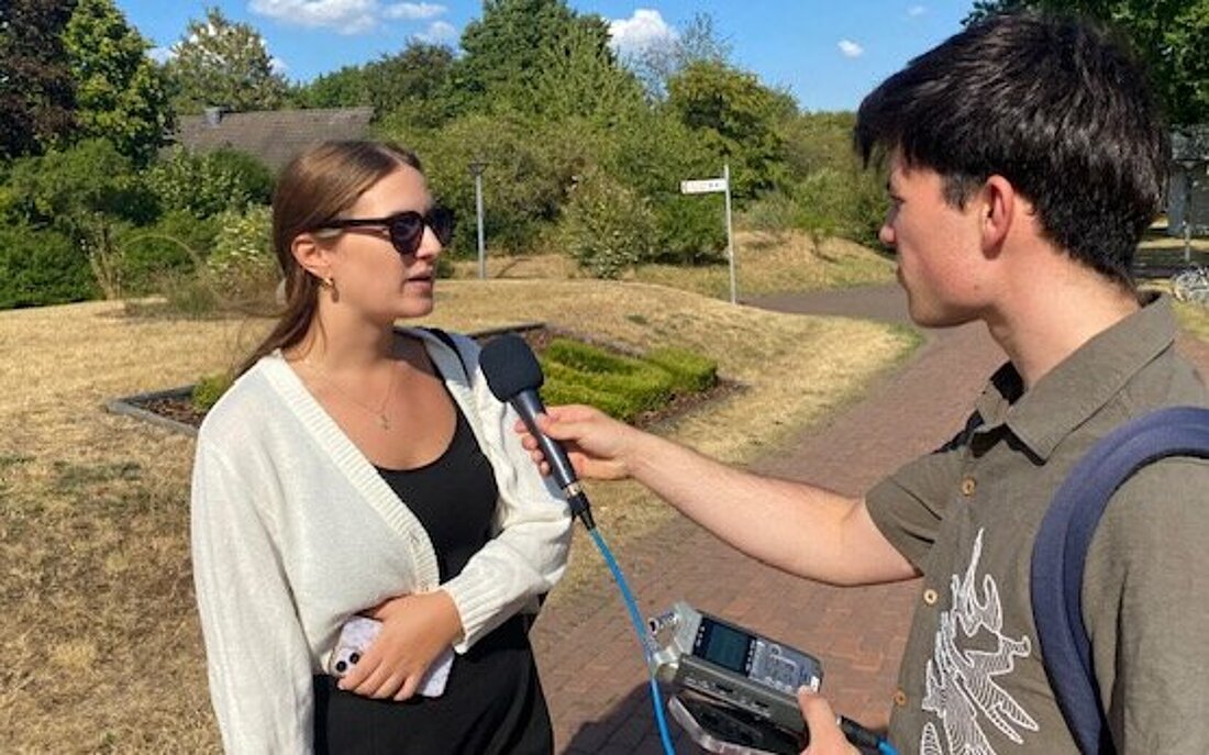 Auf dem Foto sieht man eine stehende Frau auf dem Campus, die von hochschulradio düsseldorf interviewt wird
