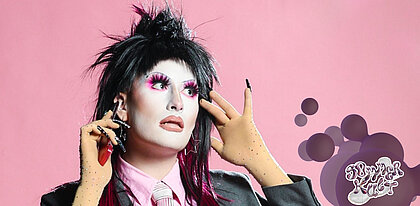 Auf dem Bild sieht man AURA mit Drag-Make Up posieren.