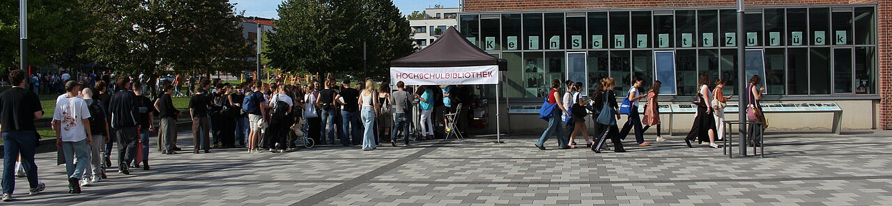 Viele Studierende stehen an dem Stand der BIB oder laufen daran vorbei. 