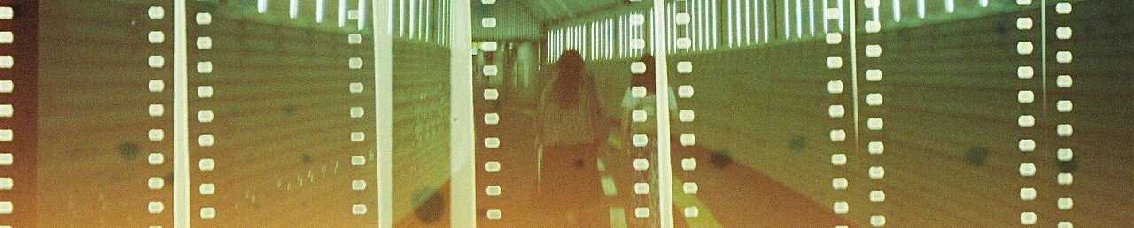 Auf dem Bild ist eine Frau von hinten fotografiert. Sie ist in einem Tunnel. Auf dem Bild liegt ein Filter, der Filmstreifen darstellt. Das Bild ist in Grünfarben getaucht.