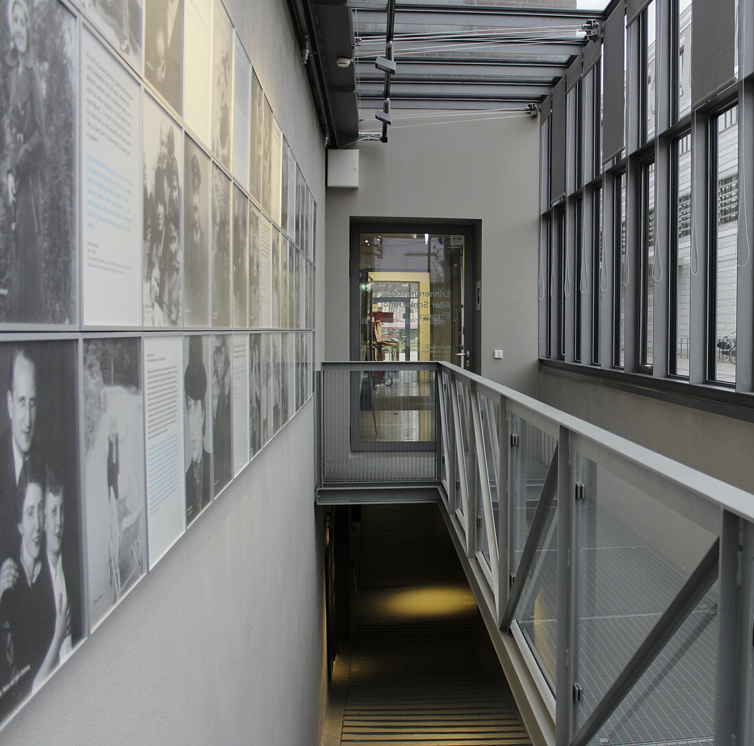 Die linke Galerie der Ausstellung zeigt die Fotos und Geschichten. Eine Treppe führt ins Untergeschoss.