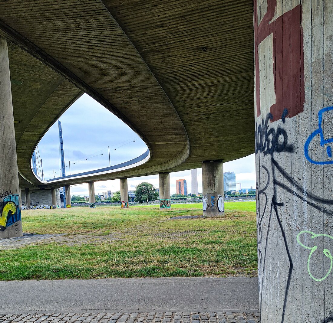 Es handelt sich um eine Aufnahme unter den Rheinbrücken, deren Pfeiler mit bunten Graffitis besprüht sind. In den Parks und am Rhein kann man wunderbar die angenehme Geräuschkulisse und die Umgebung genießen und gleichzeitig den eingerosteten Körper in Bewegung bringen. Es kann total schön sein die Zeit so sinnvoll zu nutzen und auch mal allein Düsseldorf zu erkunden.