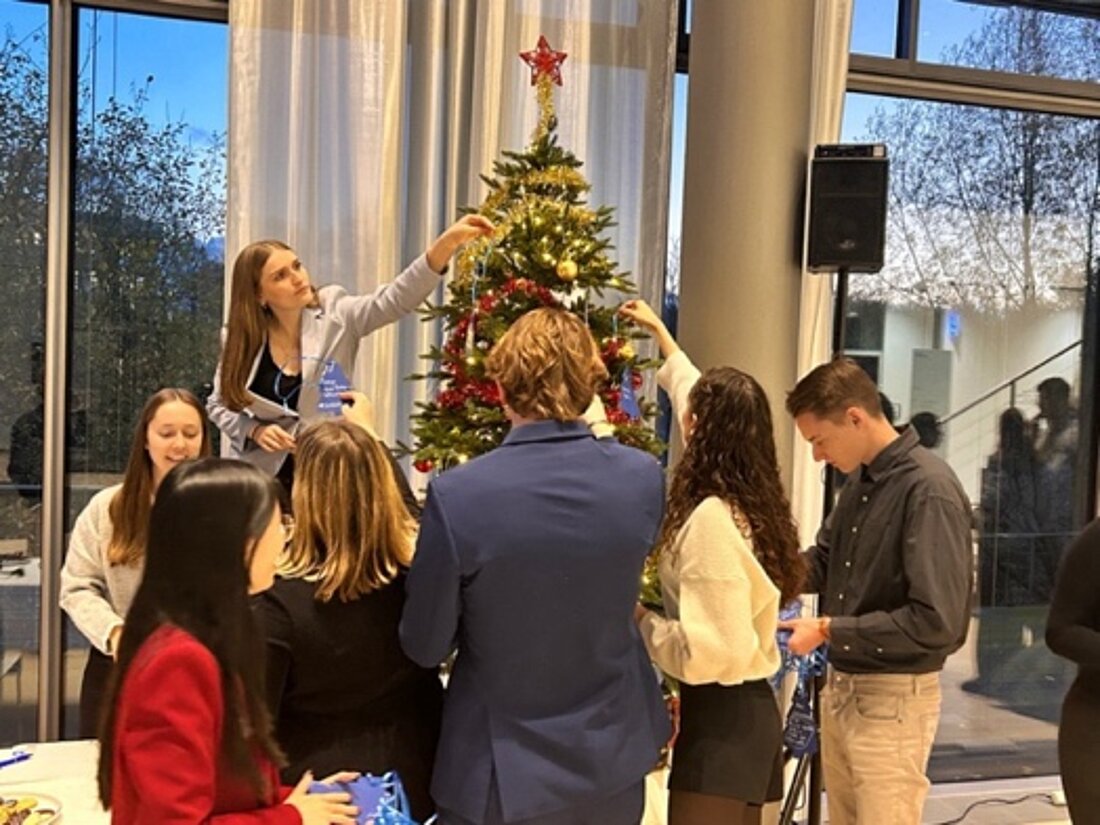 Man sieht, wie die WiWi-Fachschaft der HHU den Wunschbaum mit Wünschen schmückt.