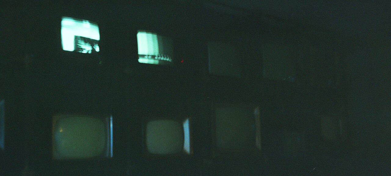 Alte Fernseher auf denen teilweise noch etwas gezeigt wird in einer dunklen Umgebung (Foto: Michelle Pieczyk)