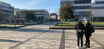 Zu sehen ist der Campus der HSD. Studierende bewegen sich auf dem Campus. 