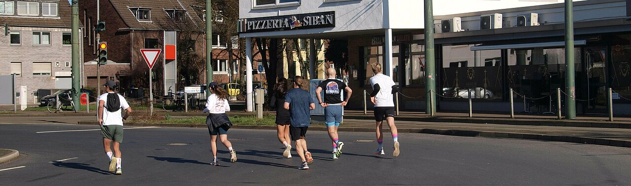 Auf dem Foto sieht man die Läufergruppe von hinten an der Vennhauser Allee, die gerade anfängt loszulaufen