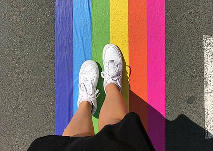 Zu sehen ist eine Regenbogenflagge als Übergang auf der Straße.