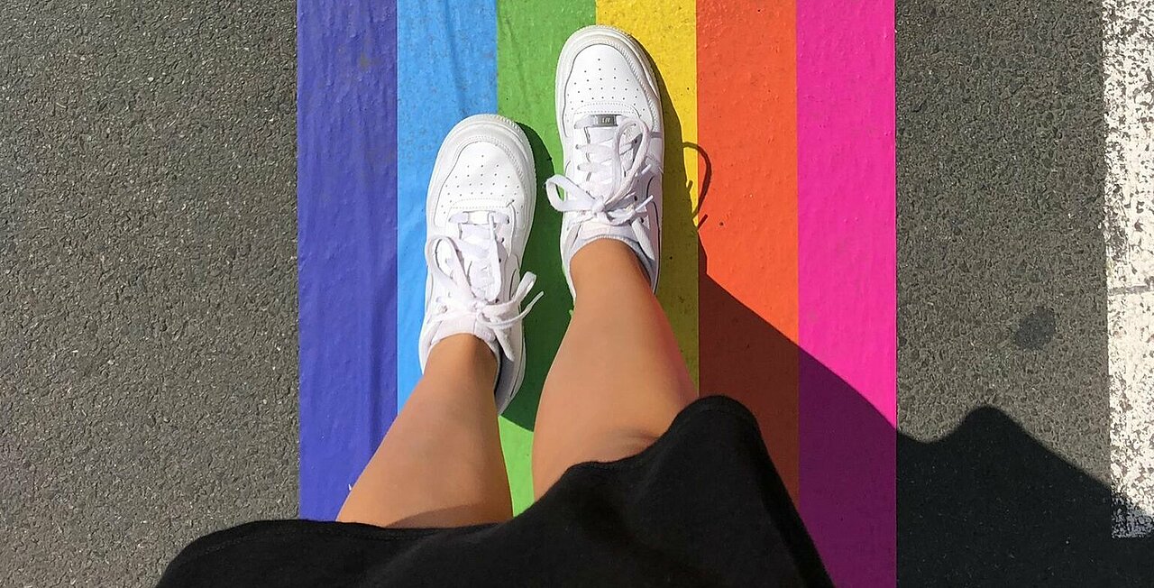 Zu sehen ist eine Regenbogenflagge als Übergang auf der Straße.