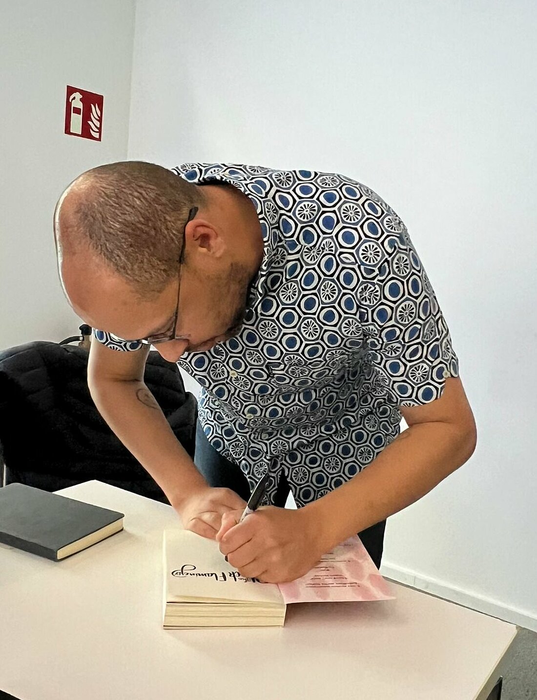 Auf dem Foto ist Autor Dean Atta zu sehen, wie der nach der Diskussionsrunde Autogramme gibt.
