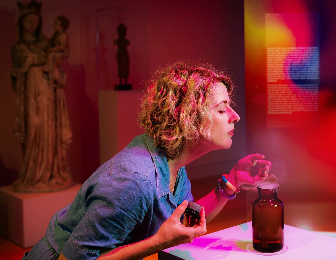 Auf dem Bild sieht man eine Frau, die an einer interaktiven Duftstation riecht.