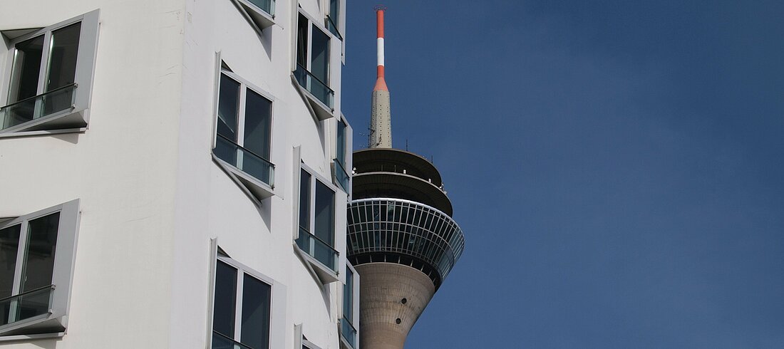 Auf dem Bild sieht man die Gebäude des Medienhafens mit dem Rheinturm im Hintergrund