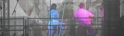 Auf dem Foto sind zwei Musiker von hinten zu sehen. Sie sitzen auf der Bühne und sind in den Farben des Art:Walk Festivals (rosa und blau) beleuchtet.