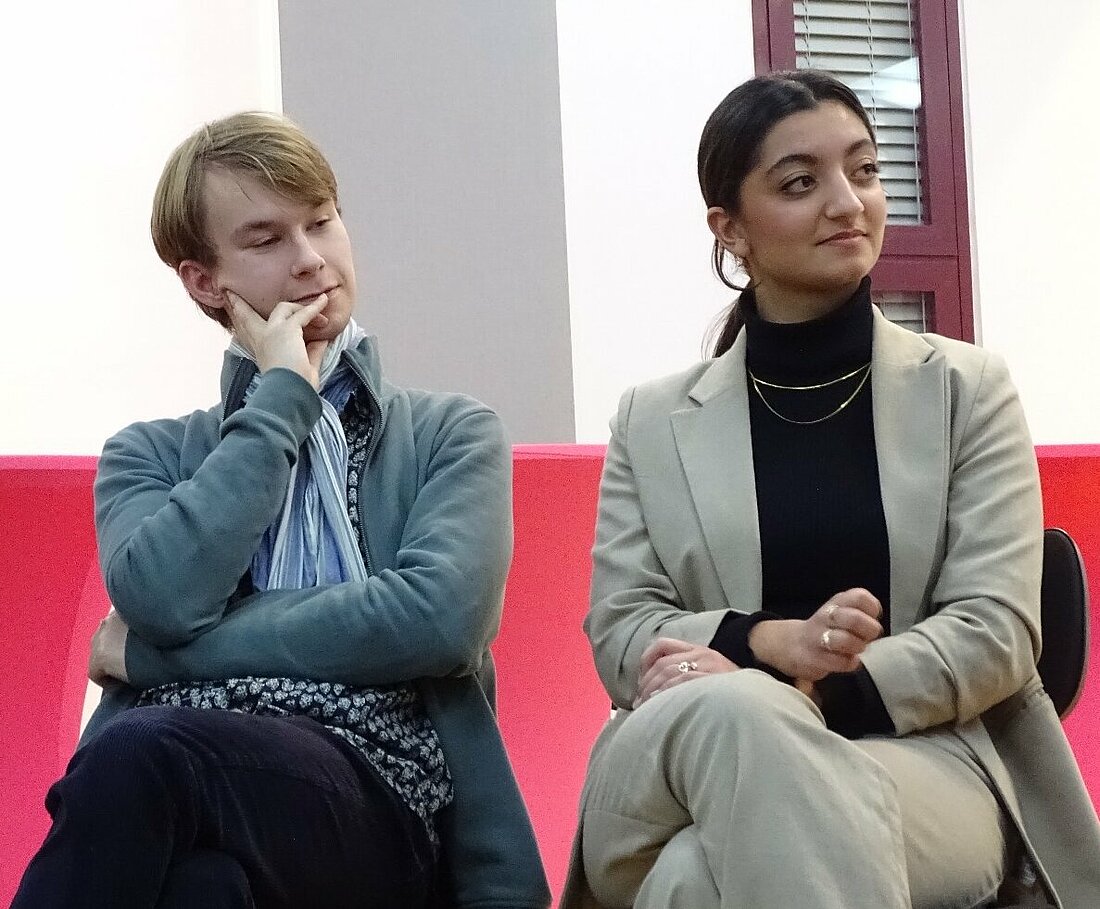 Der AStA-Vorstand sitzt während der Podiumsdiskussion zusammen und hören interessiert zu.