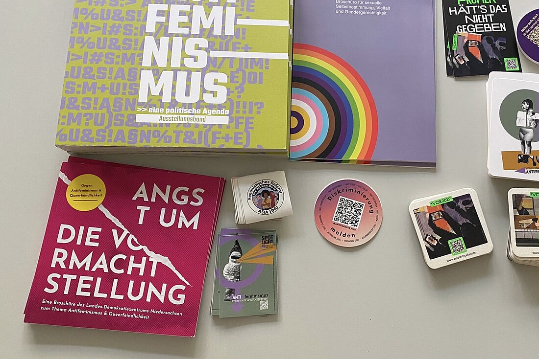 Das Bild zeigt Informationsmaterialien und Sticker, die auf einem Tisch ausgebreitet liegen.