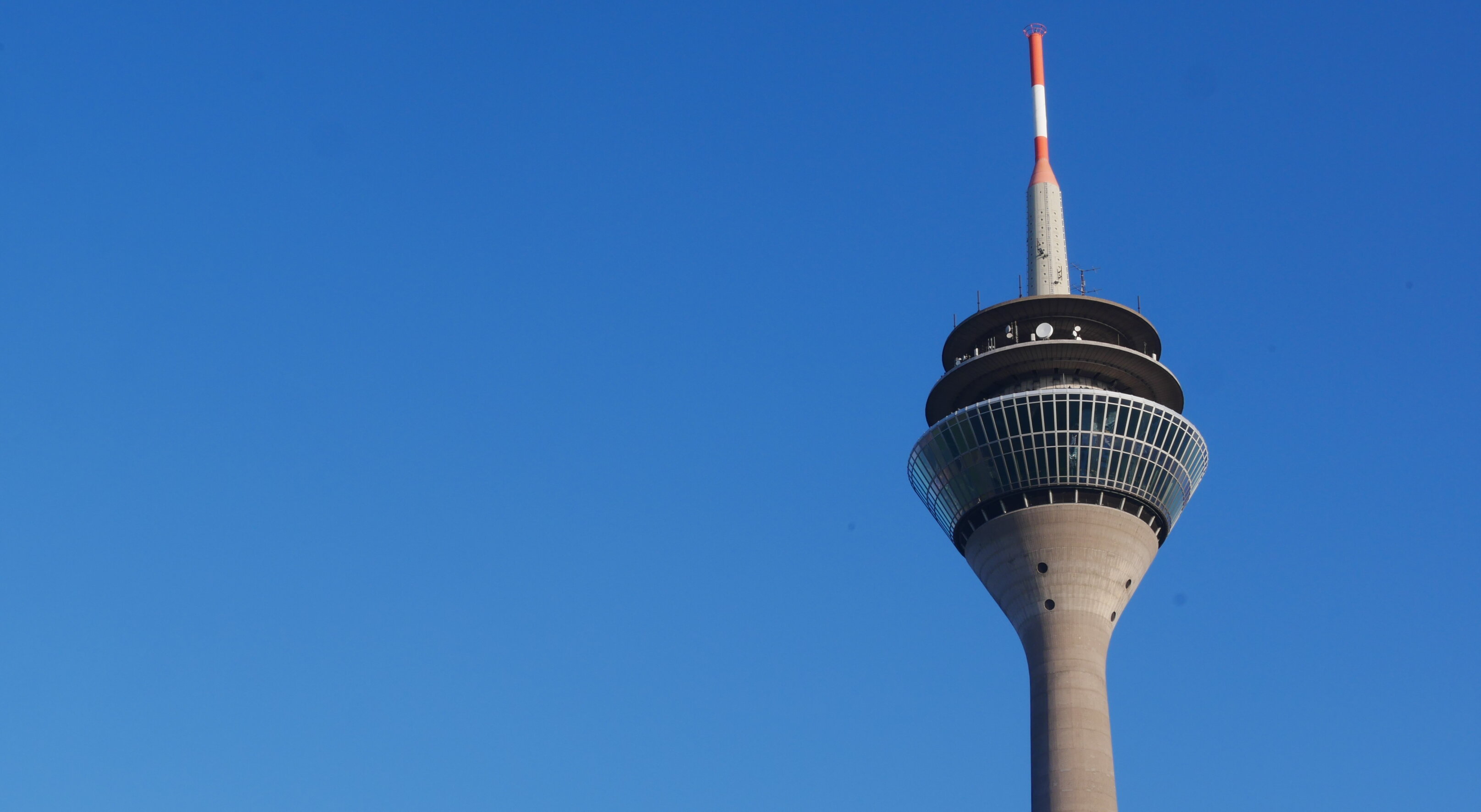 Auf dem Foto sieht man den Rheinturm in Düsseldorf vor dem blauen Himmel