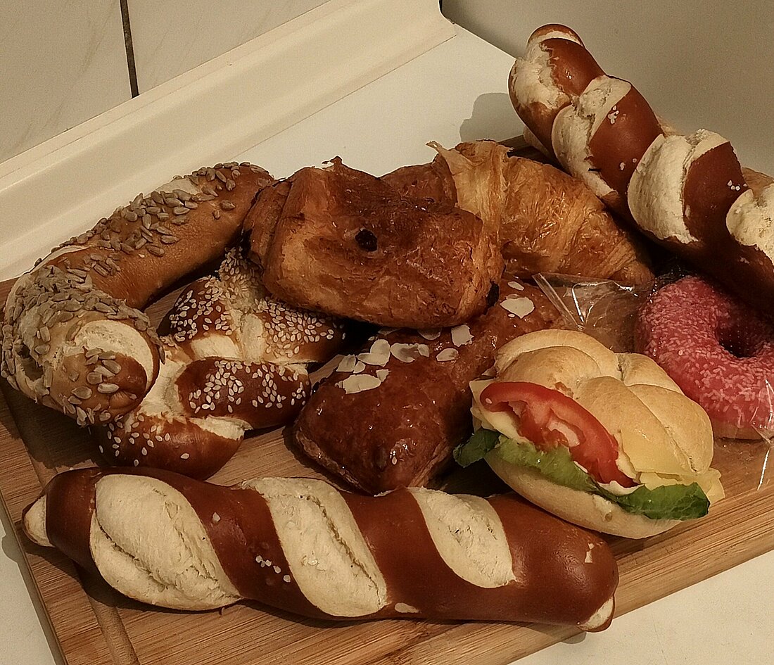 Auf einem Schneidebrett sind neun Gebäckstücke serviert, es ist eine Mischung aus süßen und deftigen Teilen.