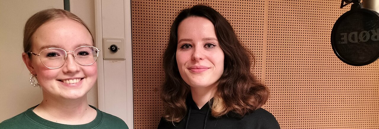 Auf dem Foto ist die Sängerin Llou und hochschulradio düsseldorf Moderatorin Hannah Vogel zu sehen. Sie stehen nebeneinander und lächeln in die Kamera.