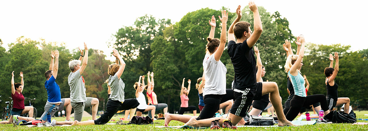 Man sieht eine Gruppe von Menschen, die Yoga machen.