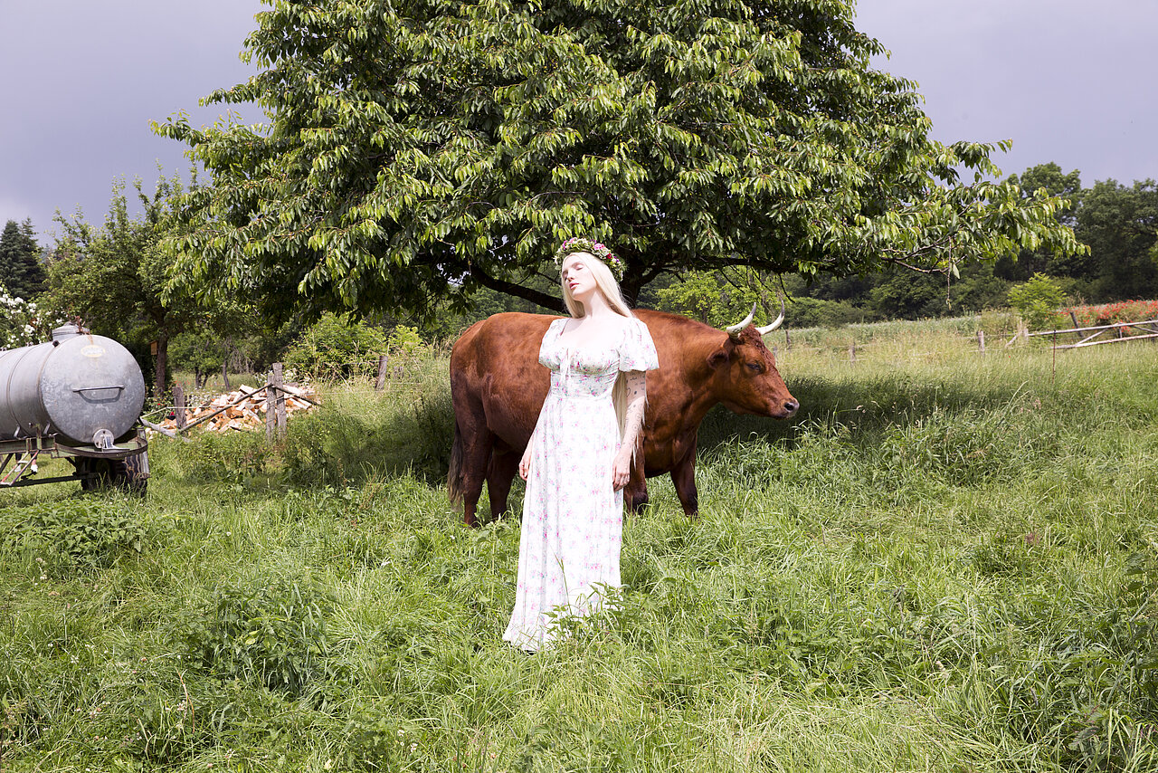 Die Künstlerin Mia Morgan steht mit einer Kuh auf einer Wiese.