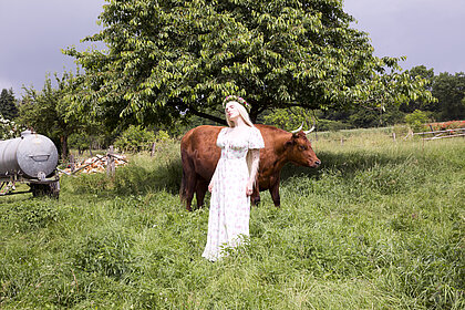 Die Künstlerin Mia Morgan steht mit einer Kuh auf einer Wiese.