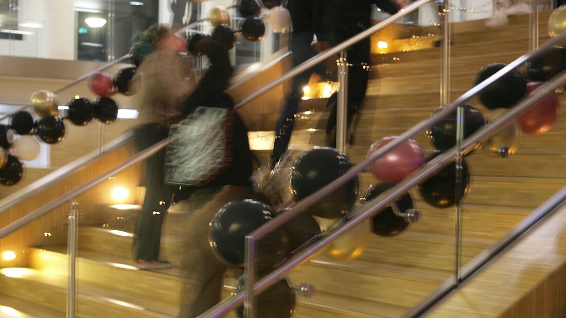 Auf dem Foto sieht man eine Treppe mit Ballons, die die Farben Farben Schwarz, Gold und Dunkelrot haben.