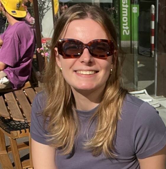 (Foto: Valeska Ridzewski) Auf dem Foto sieht man Valeska, die mit einem Kaffee an einem Tisch sitzt und in die Kamera lächelt