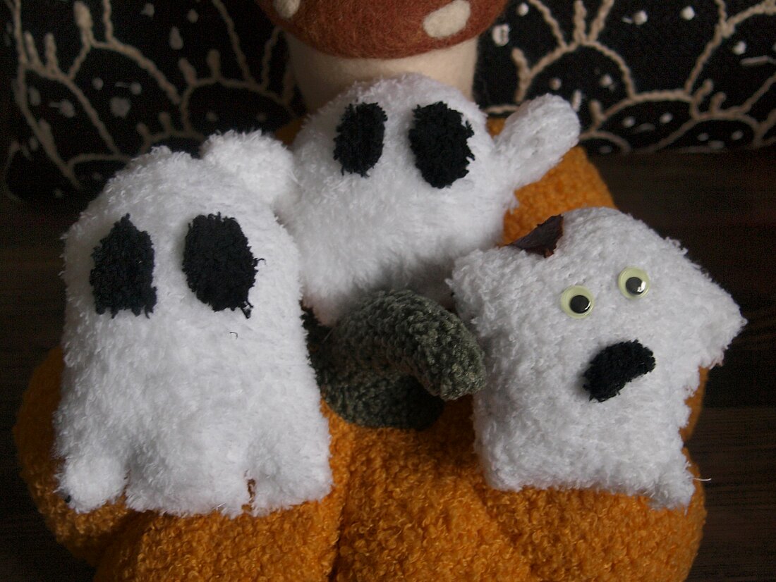 Drei verschiedene Geister-Socken auf einem Kürbis.