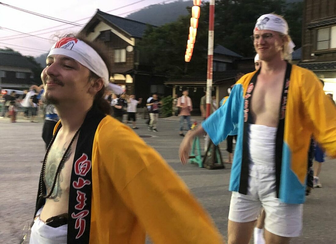 Man sieht Gunnar in typischer japanischer Festkleidung in einem Festzug mitlaufen.