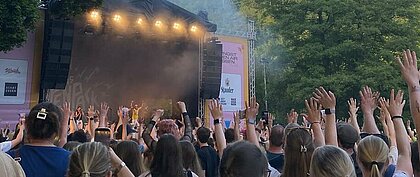 Zu sehen ist ein Publikum, welches mit hochgehobenen Händen vor der Main Stage des Pfingst Open Air 2026 steht