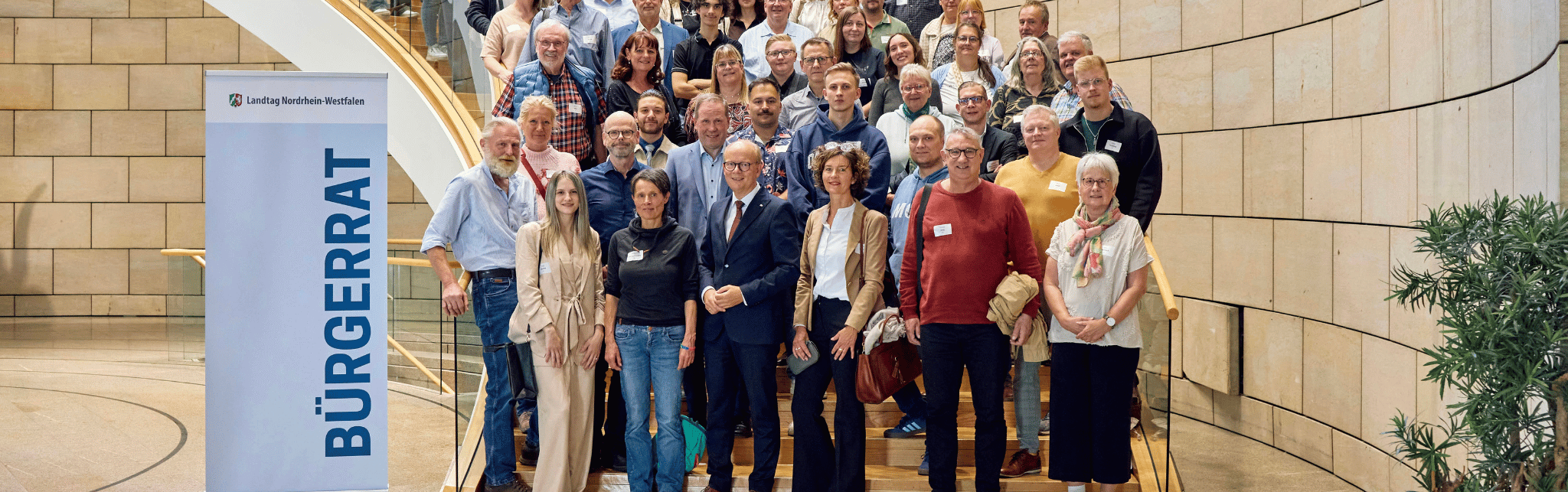 Zeigt den Bürgerrat im Landtag auf einer Treppe.
