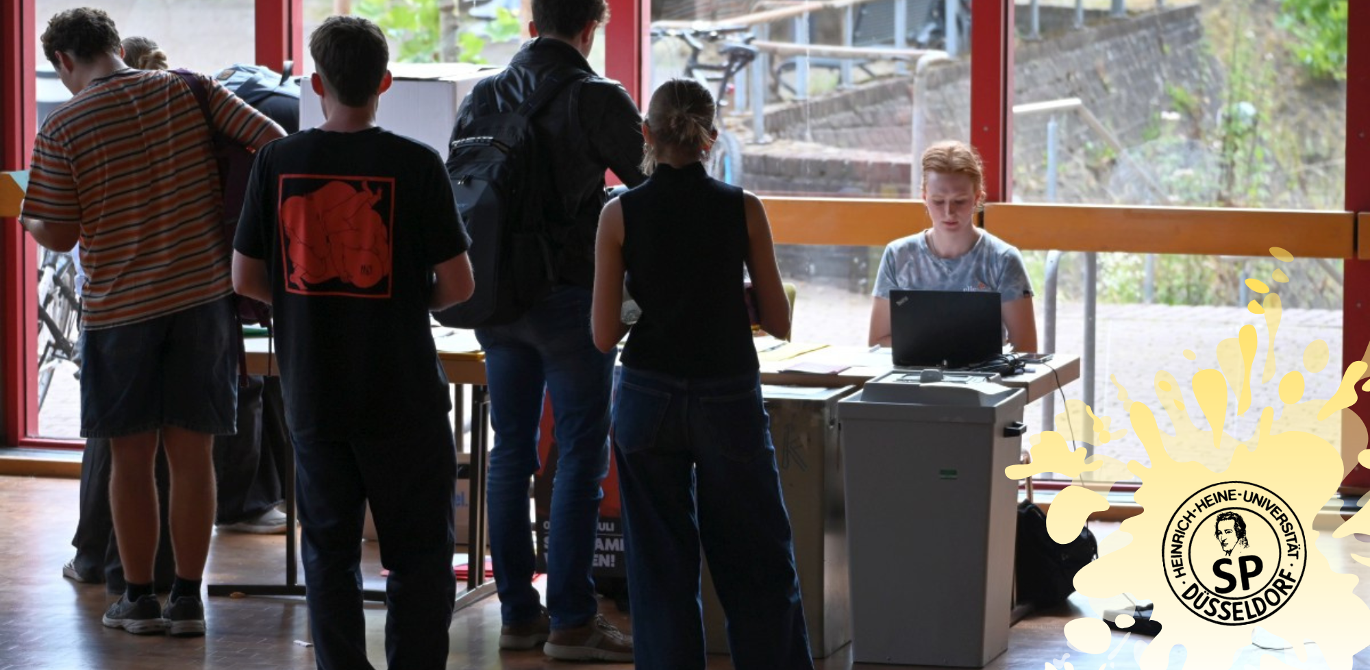 Auf dem Foto sieht man einige Personen vor einer Wahlurne auf dem Campus für die Studierendenparlamentswahl (Foto: Andreas Meske)